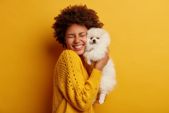 happy young woman hugging small Pomeranian