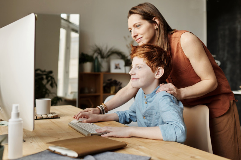 mom teaching child on computer